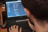 特写视图中，程序员在工作空间的笔记本电脑上输入代码