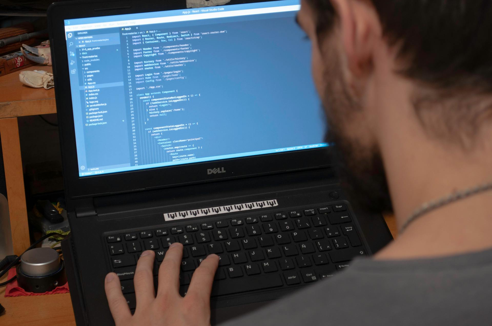 Man working on code on a laptop in an office, showcasing modern remote work setup.