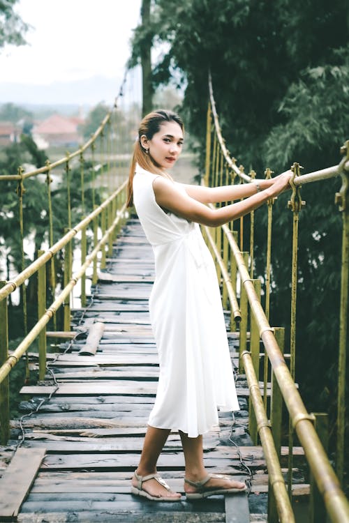 Free Woman in White Dress Standing on Wooden Bridge Stock Photo