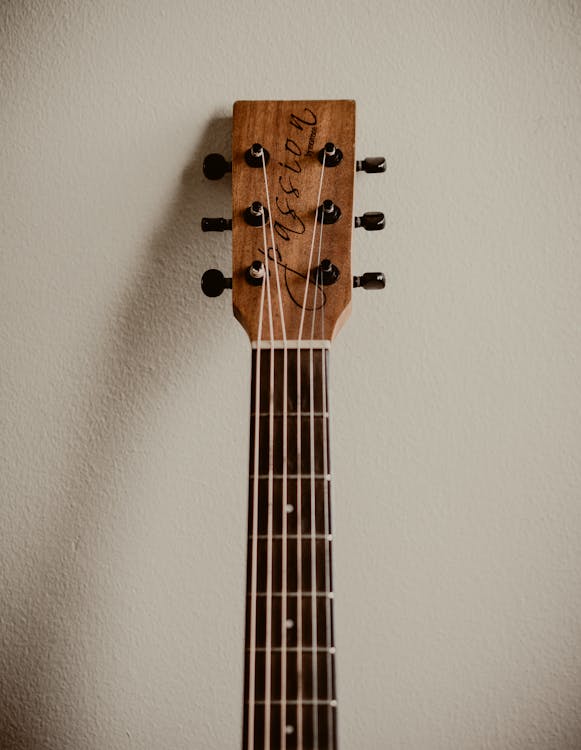 Brown Acoustic Guitar Leaning on White Wall
