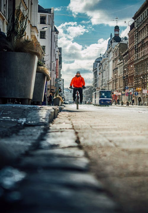 Person in Red Jacket Riding Bicycle on Sidewalk