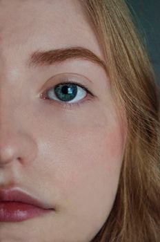 A detailed close-up portrait of a woman showcasing natural beauty with blue eyes and minimal makeup.
