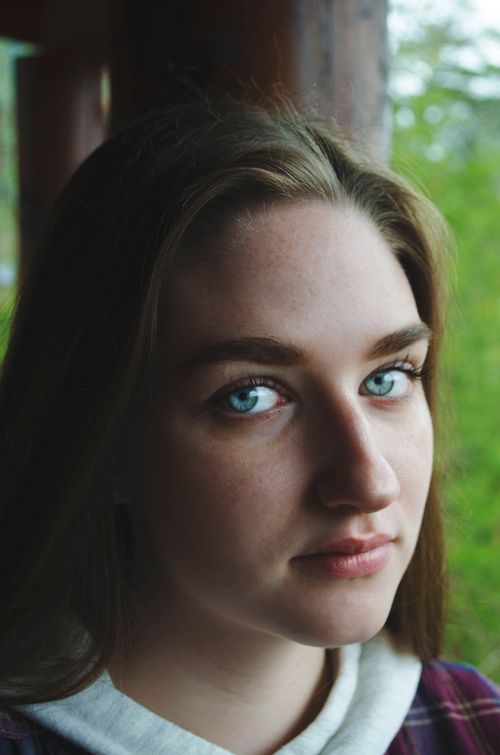 Free Close-up portrait of a woman with blue eyes and pensive expression captured outdoors. Stock Photo