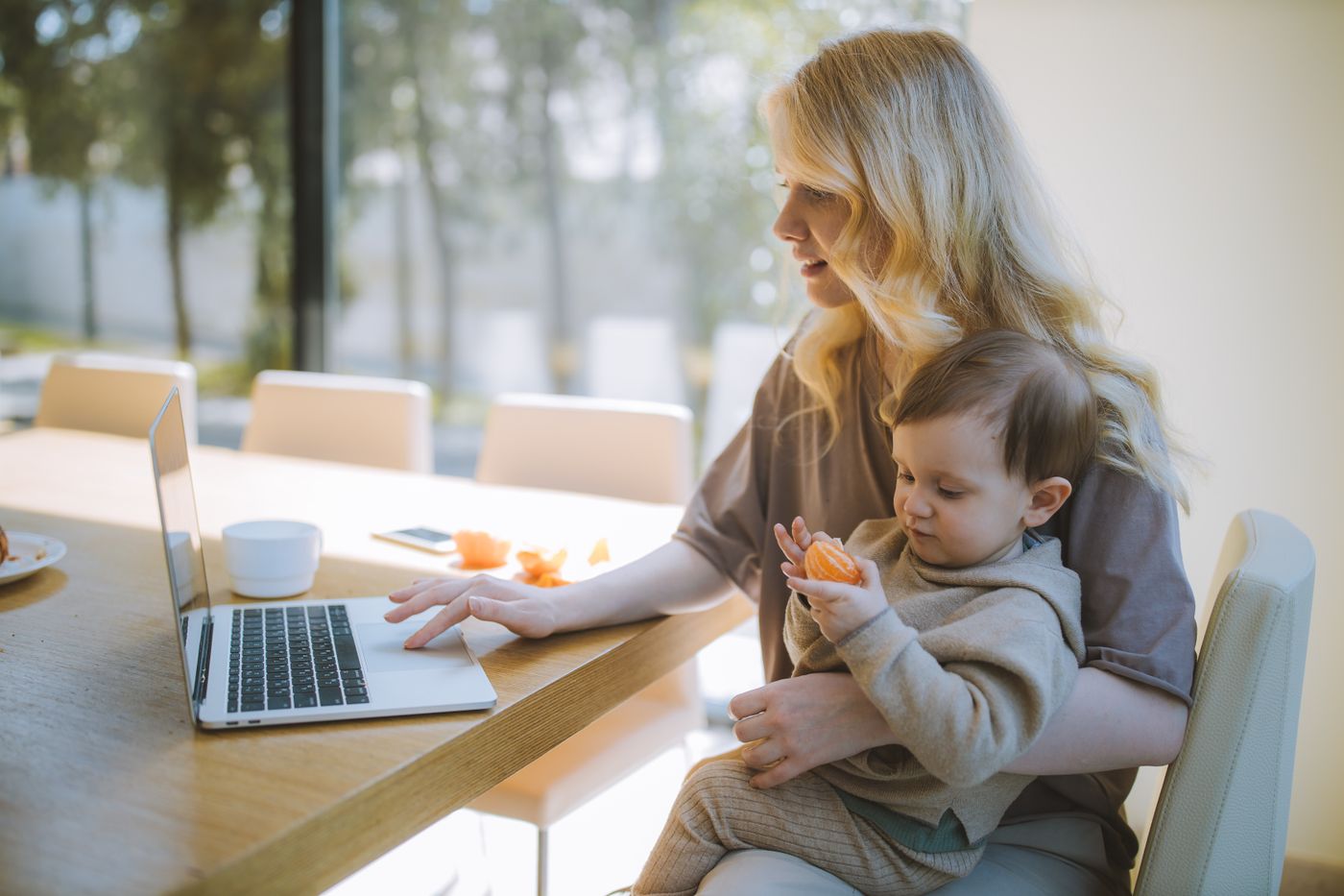Maman habillée travaillant sur son ordinateur avec son bébé confortablement installé près d’elle