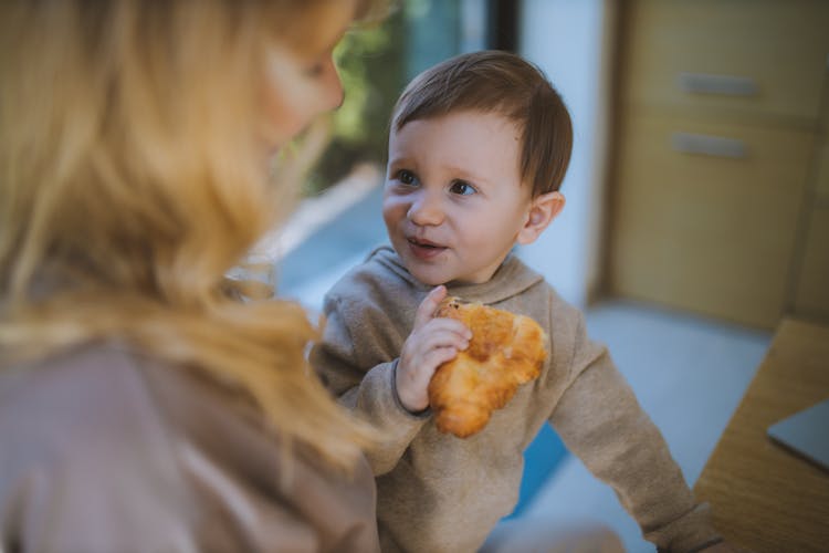 Baby Boy Eating A Croissant With His Mother