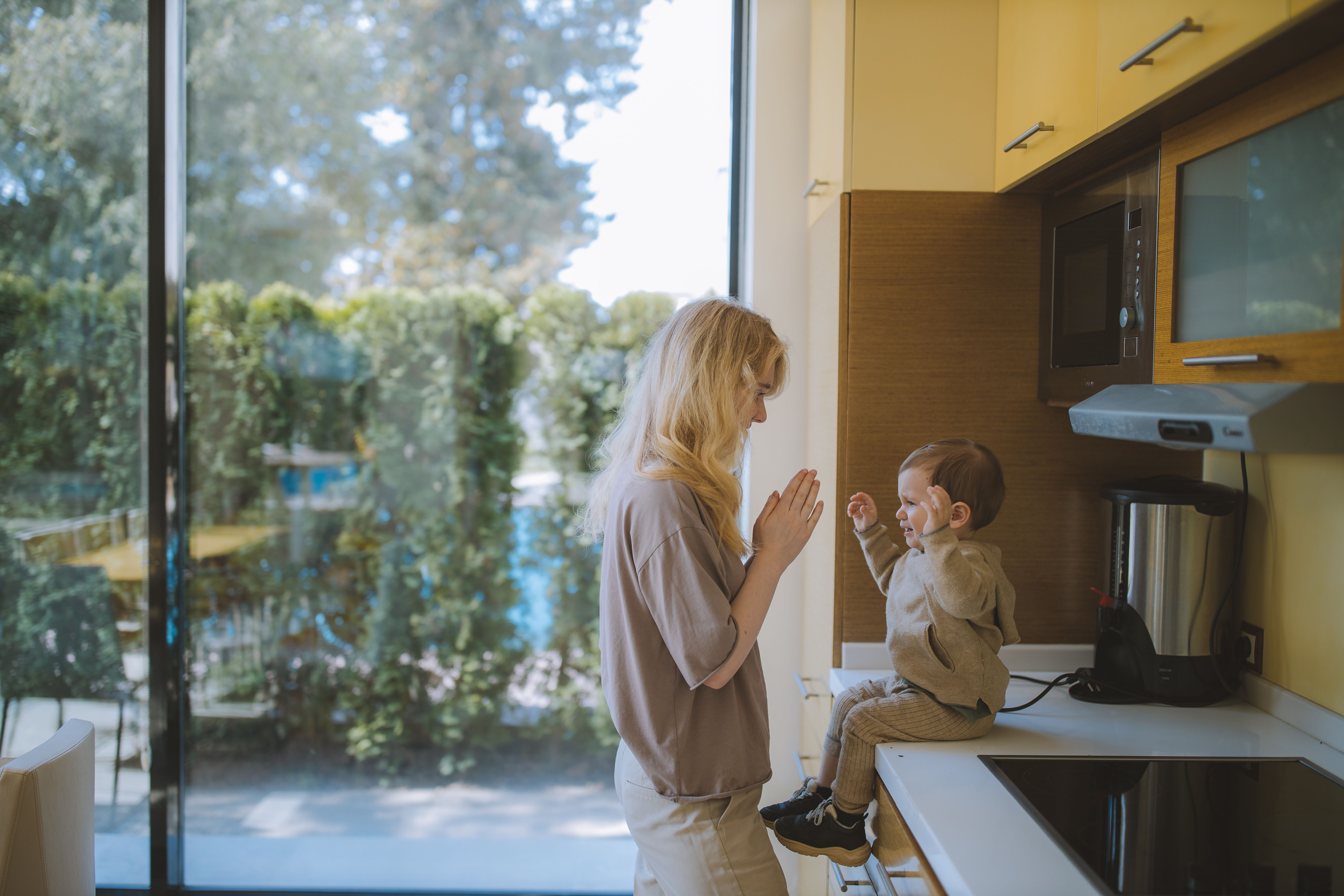 A joyful moment of a mother and child playing together in a bright kitchen. - Photo by Anastasia  Shuraeva on Pexels
