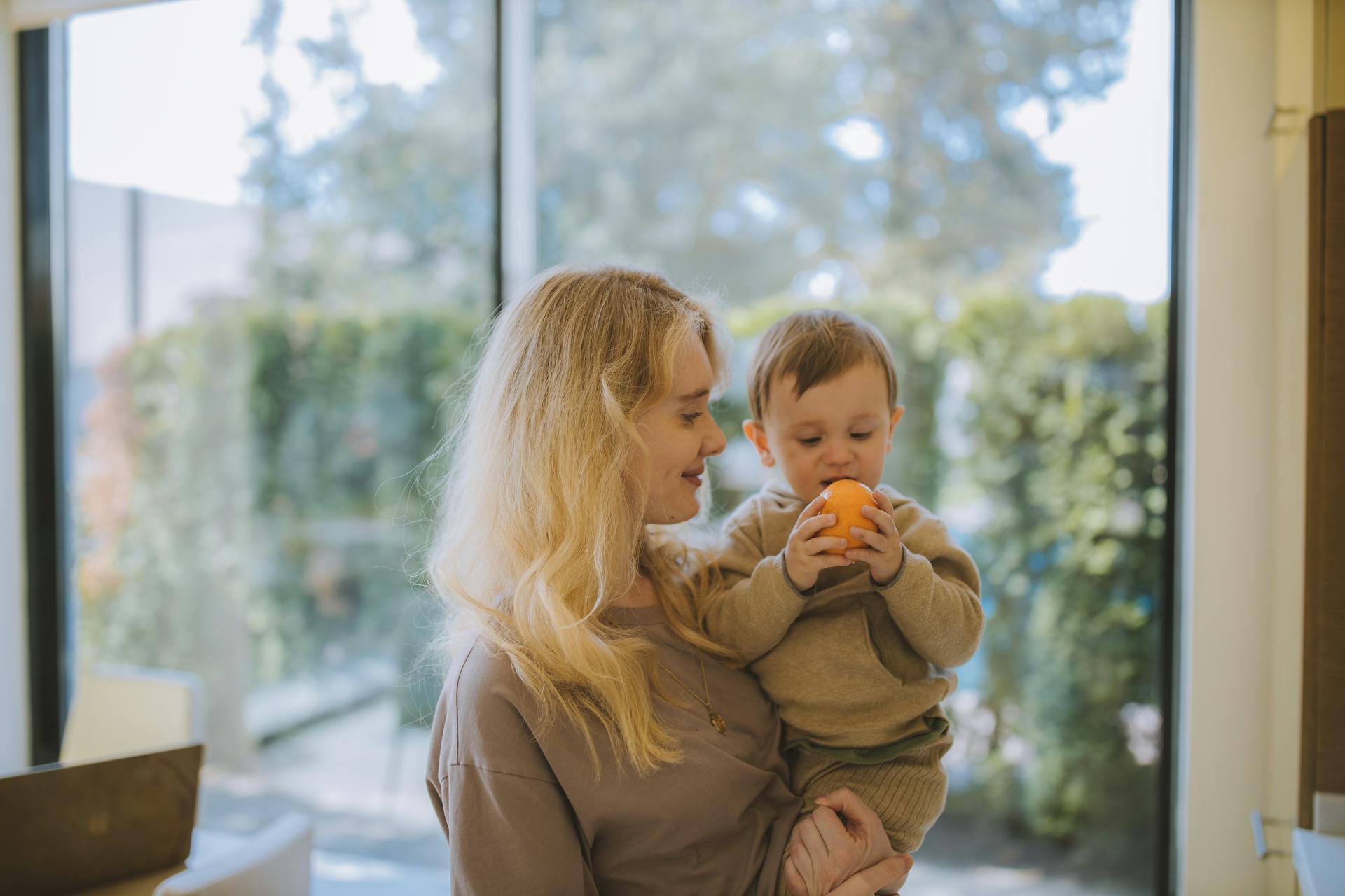 Woman Carrying Baby With a Tangerine