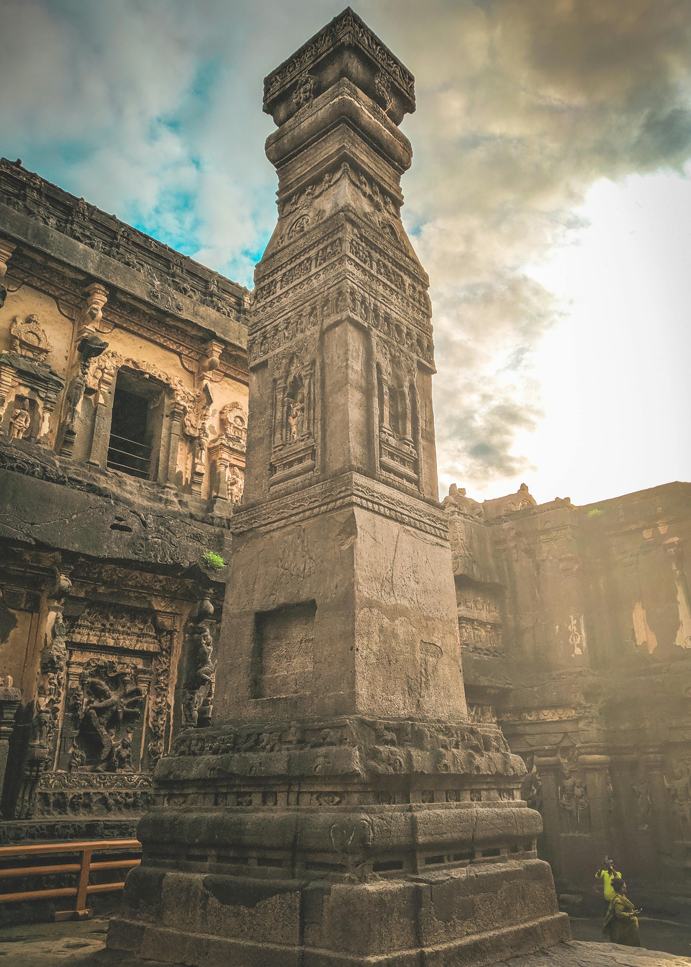 From below of ancient stone monument located in yard of abandoned oriental historical complex against cloudy sky in sunny day