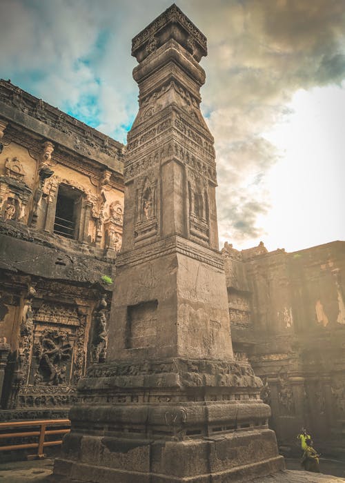 Free From below of ancient stone monument located in yard of abandoned oriental historical complex against cloudy sky in sunny day Stock Photo
