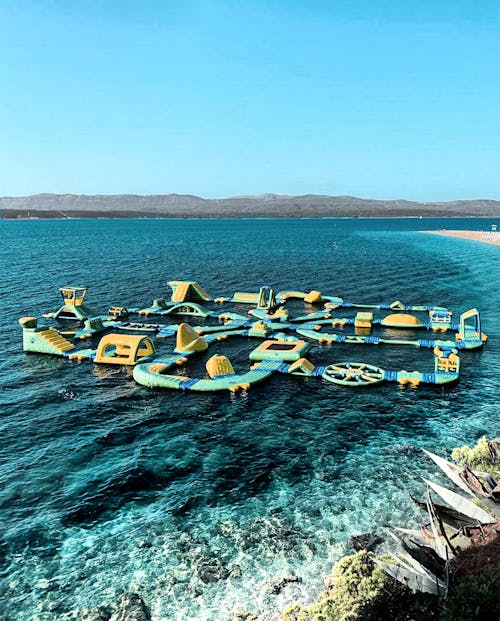 Yellow and Green Floating Water Playground on Blue Sea Under Blue Sky