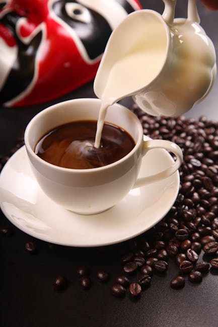 White Ceramic Pitcher With White Cream Pouring on Black Coffee Mug