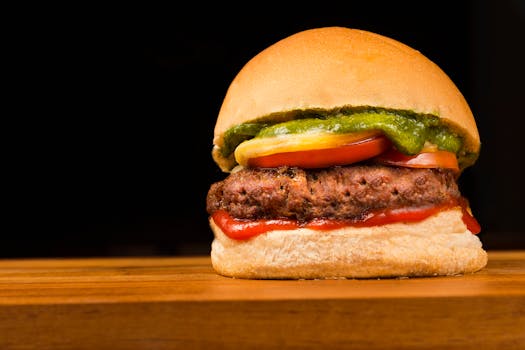 Delicious close-up of a juicy hamburger with toppings on a wooden table, ideal for food photography.