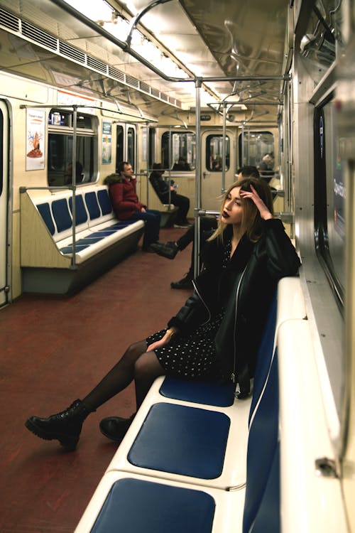 Woman in Black Leather Jacket Sitting on Blue and White Train Seat