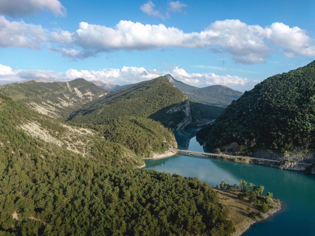 Munți verzi lângă un lac, sub cer albastru