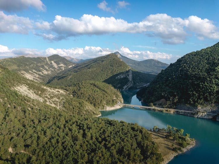 Green Mountains Near Lake Under Blue Sky