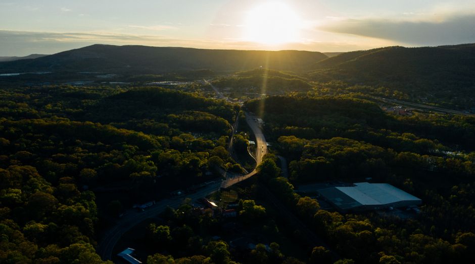 Incredible Lookout Mountain Grand Aerial Experience Review: A Spectacular Tennessee Helicopter Tour Review 2026 - Drone shot of a sunlit road winding through lush forest and hills near Chattanooga, Tennessee.