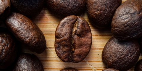 Macro shot showcasing roasted coffee beans on wooden surface for a rich, aromatic appeal.