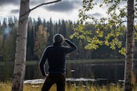 Man in Black and Gray Striped Long Sleeve Shirt Standing Near Body of Water