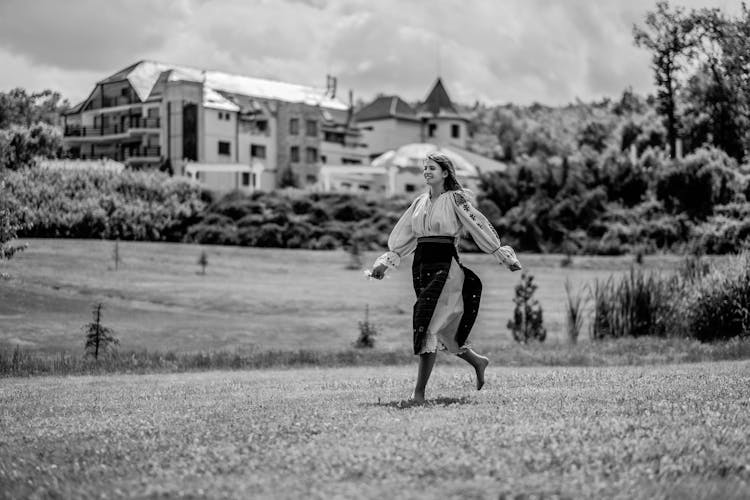 Smiling Girl In Dress Running On Grass