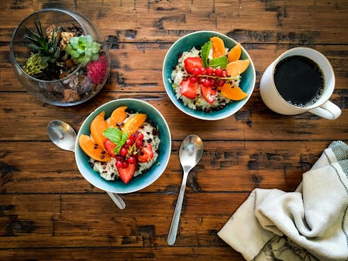 Free Coffee Cup and Bowls with Fruit Salad Standing on a Wooden Table  Stock Photo