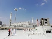 Unrecognizable Muslim pilgrims near ancient mosque on sunny day