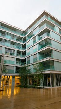 Contemporary residential building featuring glass balconies against an urban backdrop.