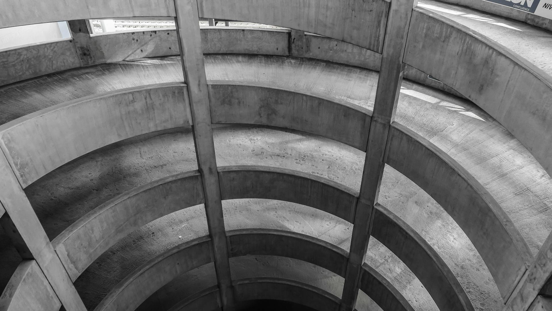 Black and white photo capturing the abstract curves of a concrete spiral ramp structure.