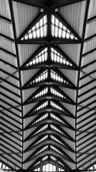Dramatic black and white photo of a church ceiling with geometric patterns and strong lines.