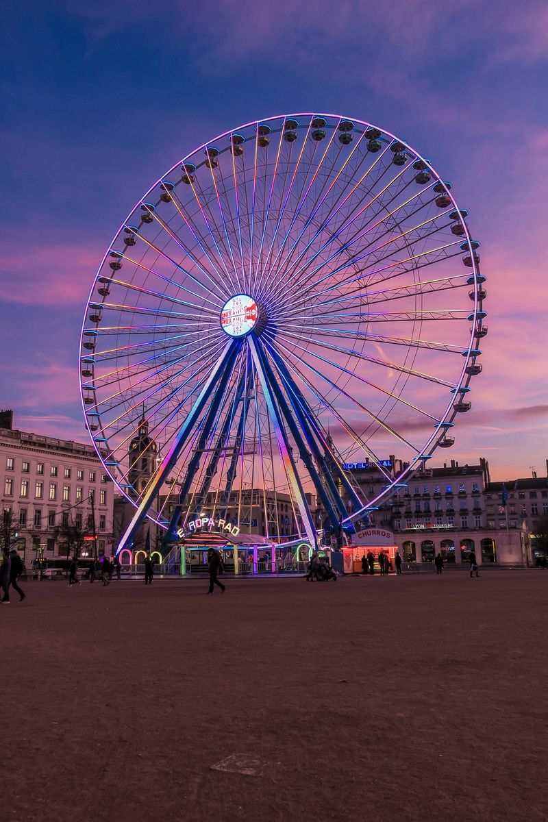 Ferris wheel on Place Bellecour square in Lyon at dusk