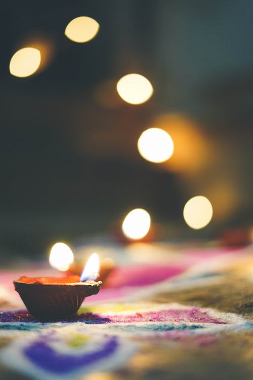 Closeup of small burning candle placed on colorful carpet during traditional Buddhist Vesak holiday celebration at night