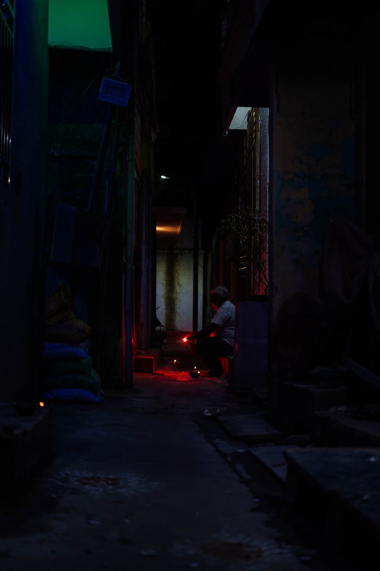 Unrecognizable People Relaxing On Porch Of Shabby Building In Evening