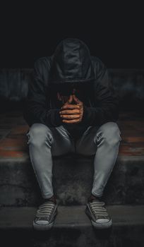 晚上，一名穿着连帽衫的男子独自坐在台阶上沉思