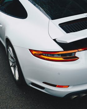 Elegant white sports car with a glossy finish parked outdoors on a rainy day.