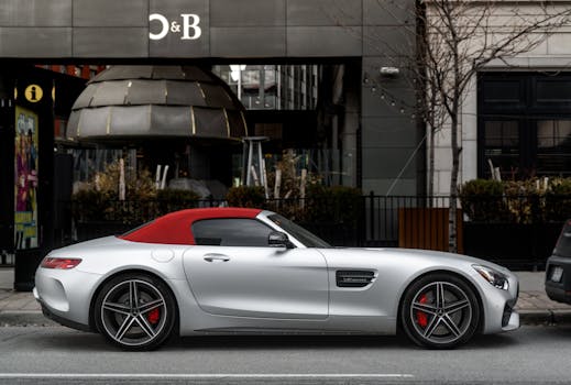 A sleek silver luxury convertible with a red top parked downtown Toronto, showcasing style and elegance.