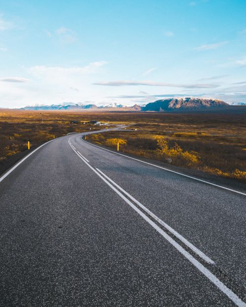 Free A winding road in Iceland offers breathtaking views of distant mountains and clear skies. Stock Photo