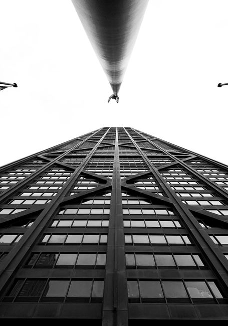 Black and white low angle of modern high tower with reflecting windows located in contemporary city
