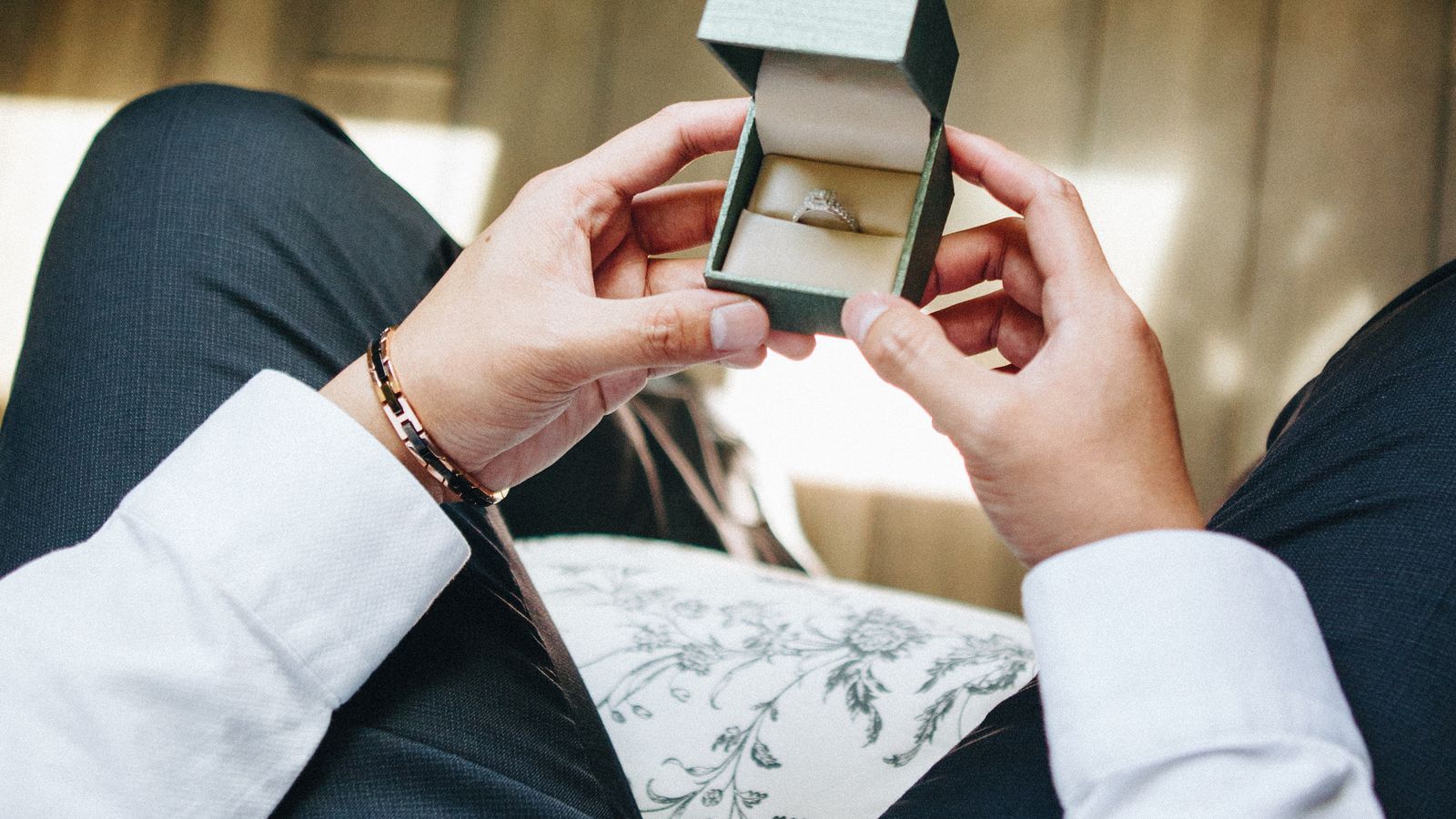 Hands holding an open box containing a ring
