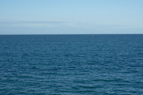 Free A calm and expansive ocean view with gentle waves beneath a clear blue sky. Stock Photo