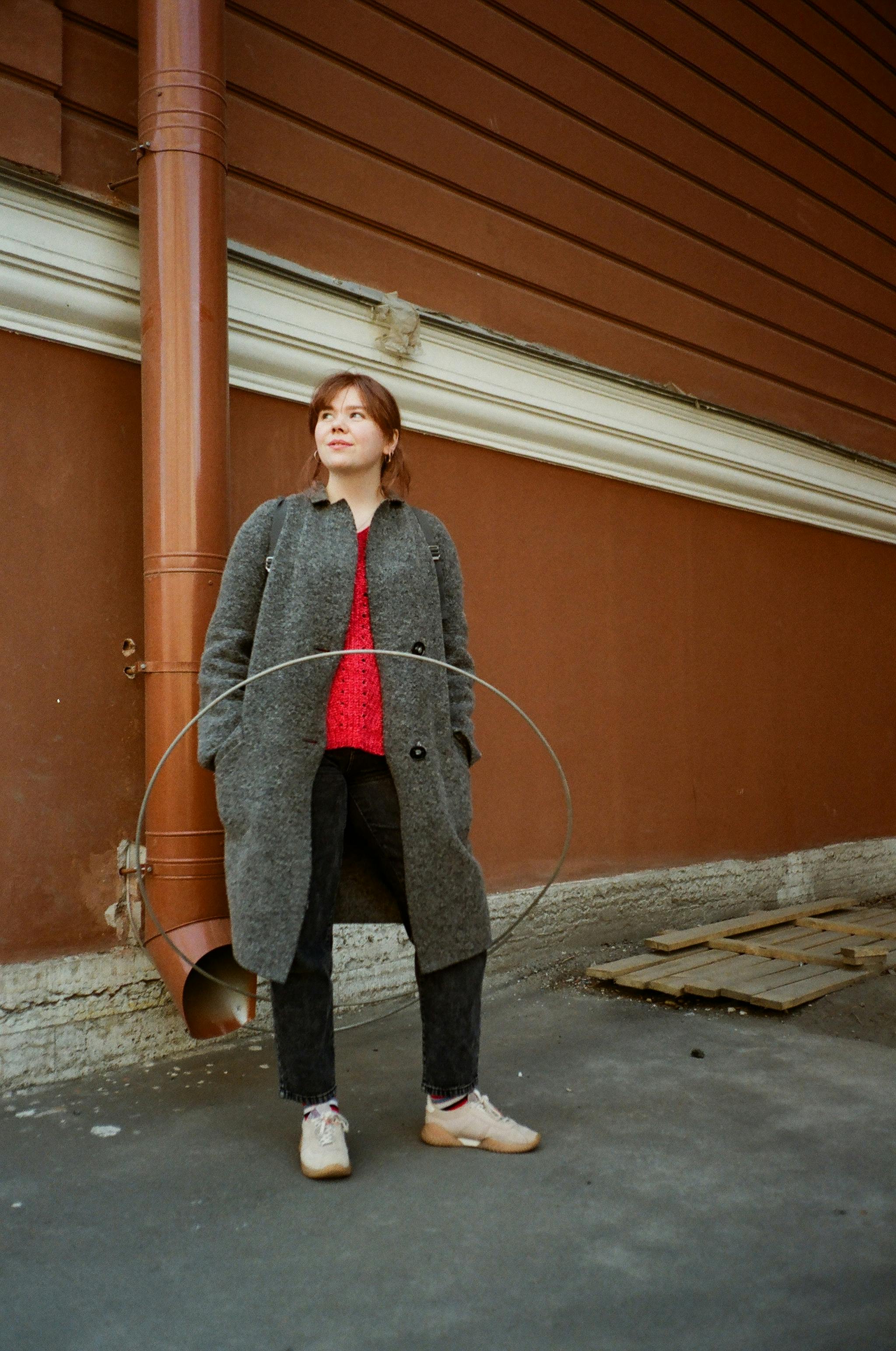 dreamy woman with hoop near drain pipe on house wall