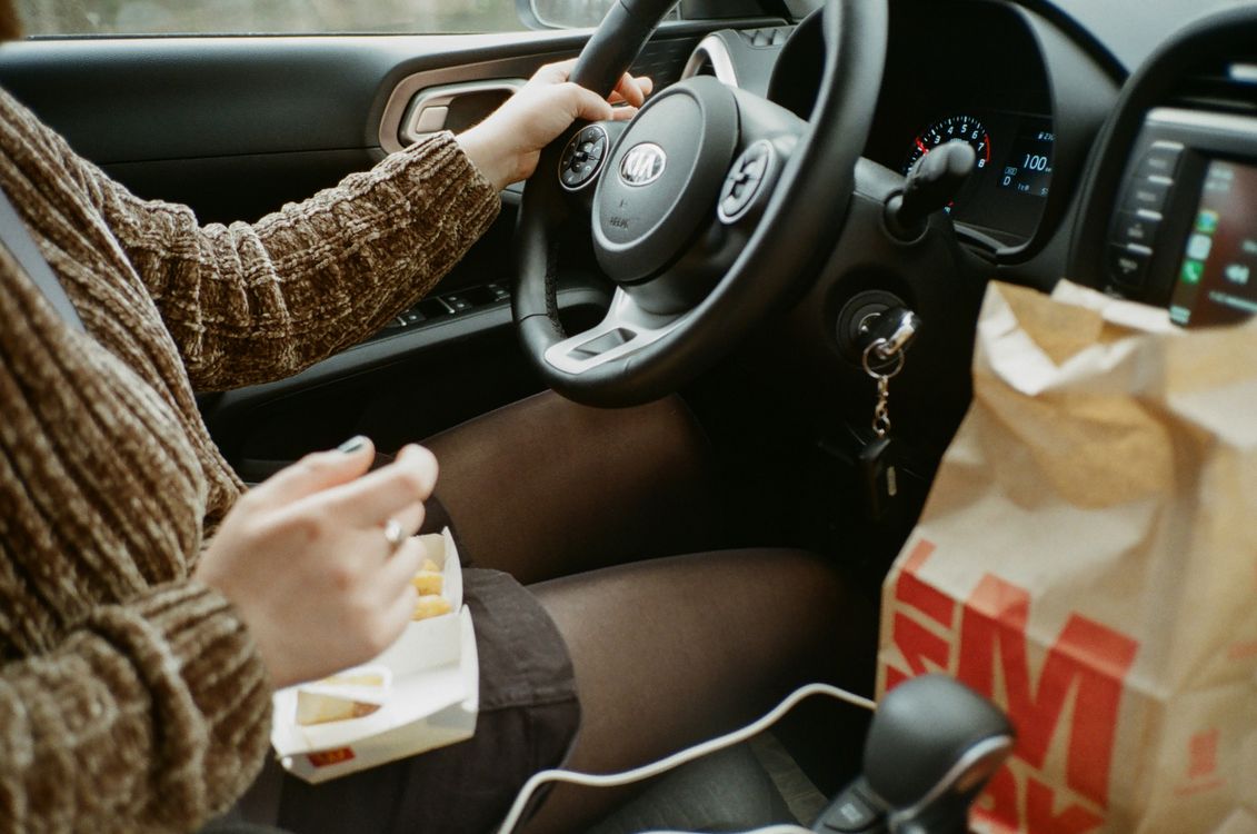 Person in Brown Long Sleeve Shirt Driving and Eating
