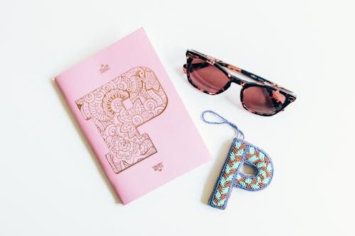 Black Framed Sunglasses Beside Pink Notebook and Letter P Decor