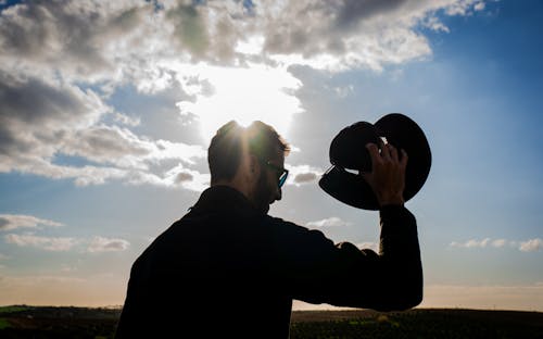 Silhouette of Man Holding a Hat