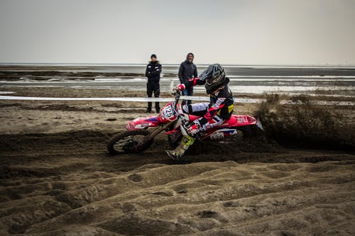 Man in Black Jacket Riding Red and White Motocross Dirt Bike