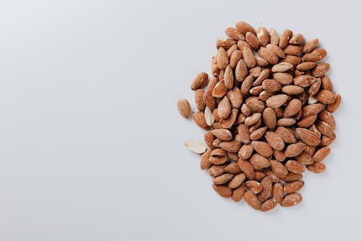 白色表面上堆着一堆生杏仁，非常适合作为健康零食或用于食品摄影