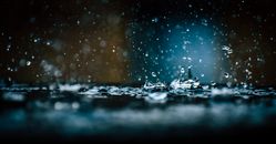 在黑暗、阴郁的背景下，特写镜头捕捉了雨滴飞溅在表面的瞬间