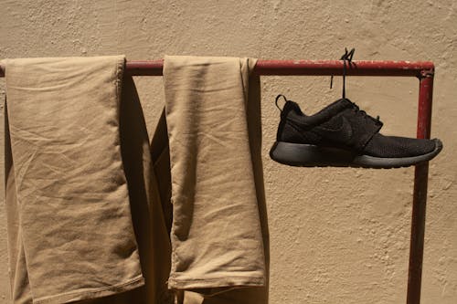 Brown Pants and Black Shoe Hanging on Red Metal Rack