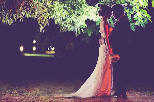 Woman in White Dress Standing Beside Man in Black Suit