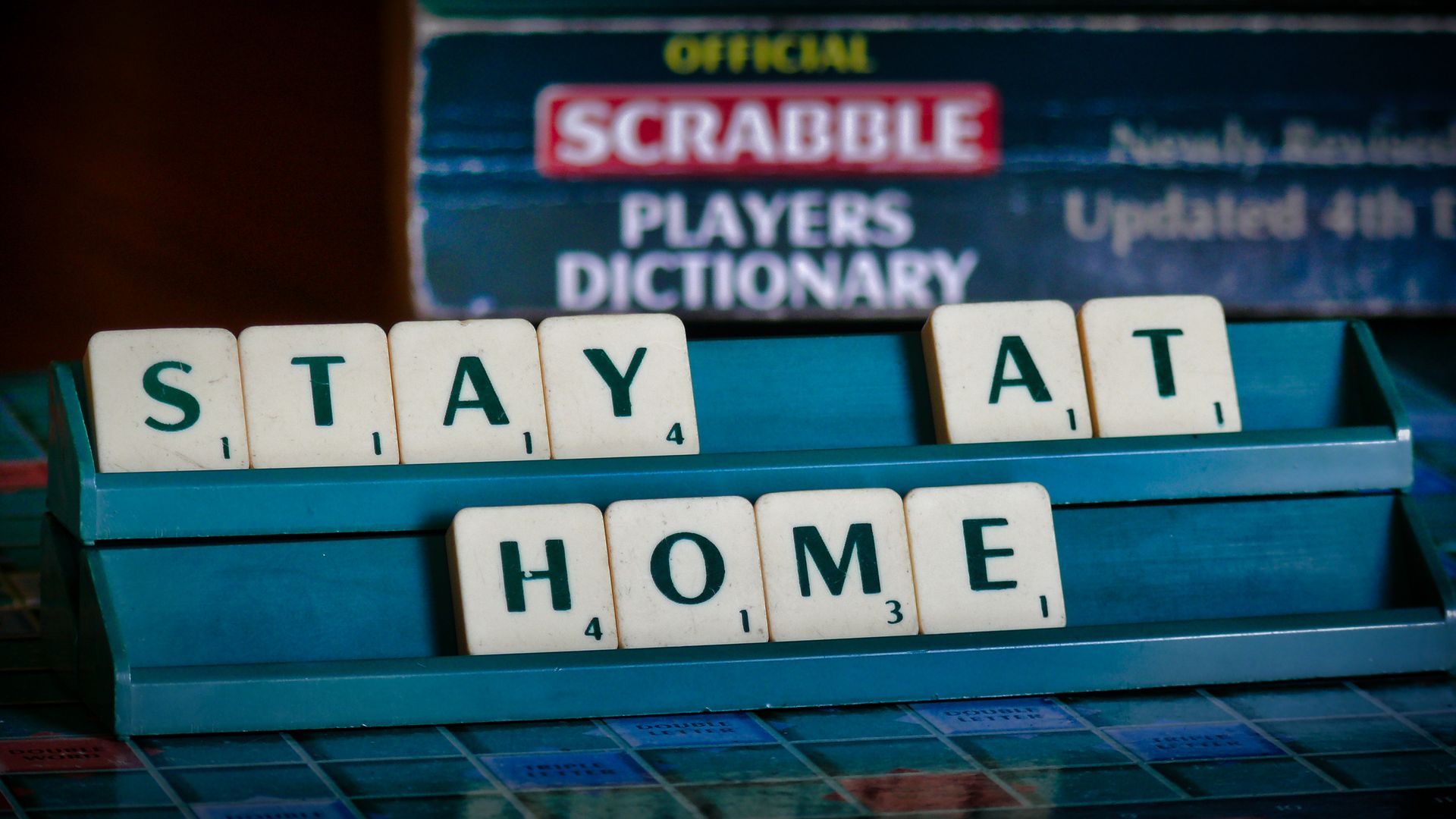 Scrabble tiles spell 'Stay At Home' for COVID-19 safety awareness.