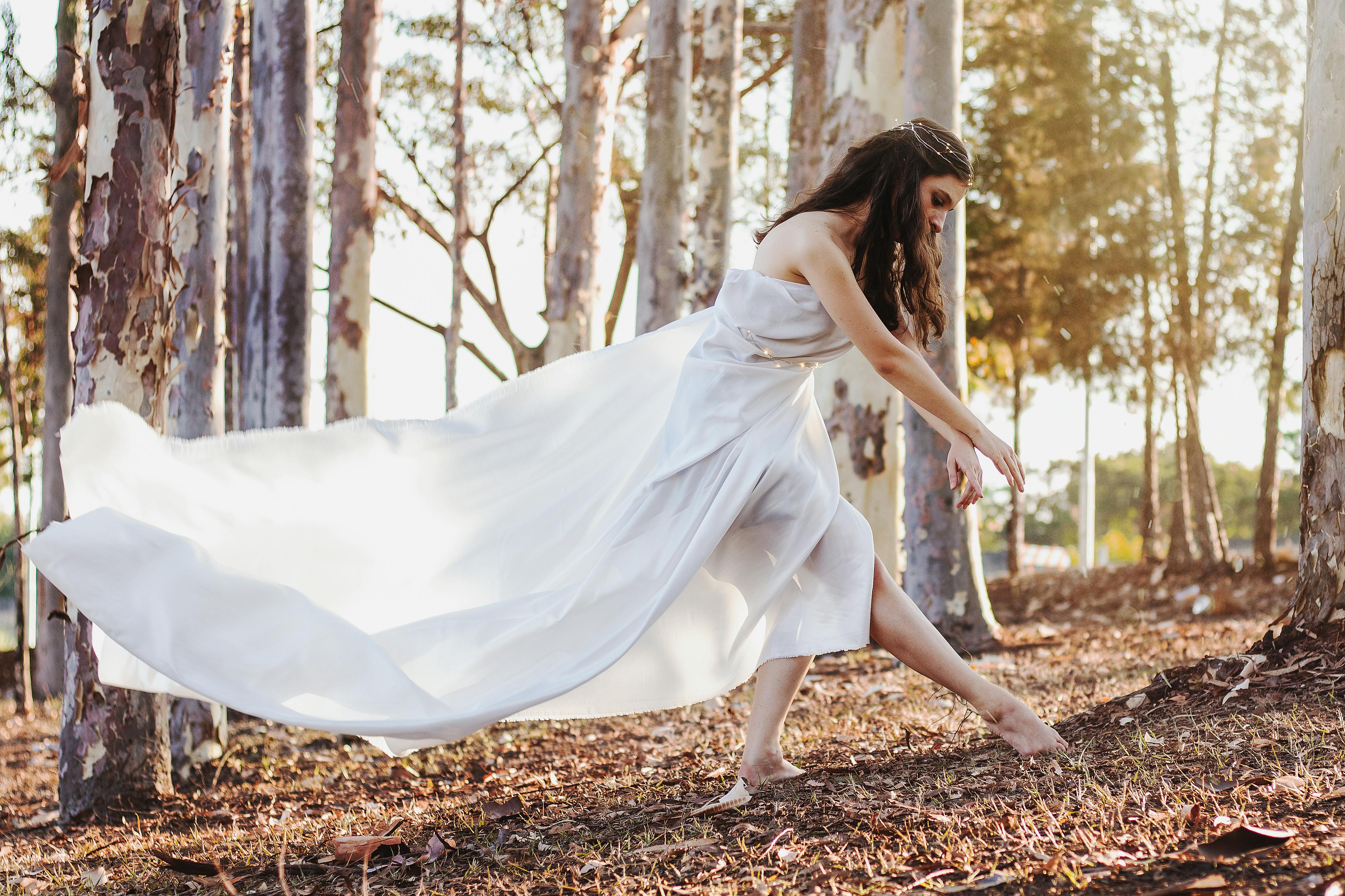 woman in white dress standing on brown dried leaves