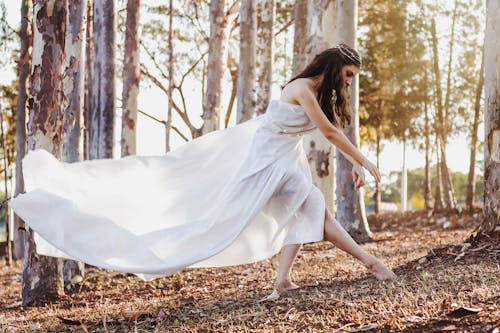 Woman in White Dress Standing on Brown Dried Leaves